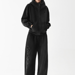 Full body shot of a male model wearing an oversized black zip-up hoodie and matching wide-leg sweatpants