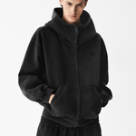 Close-up of a male model wearing a black zip-up hoodie with hands in pockets.