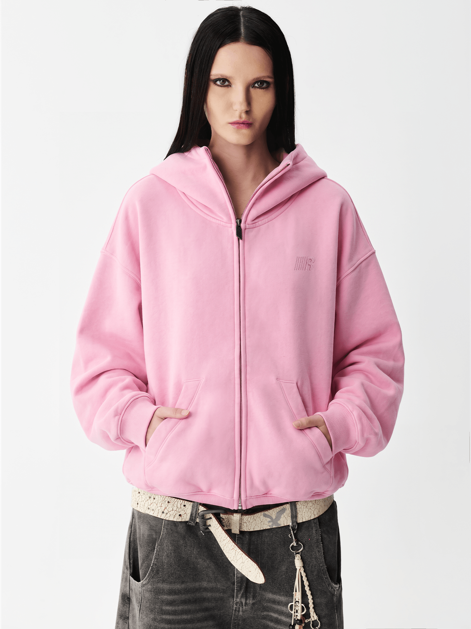 Close-up shot of a female model wearing a pink hoodie with the hood pulled up over the face.