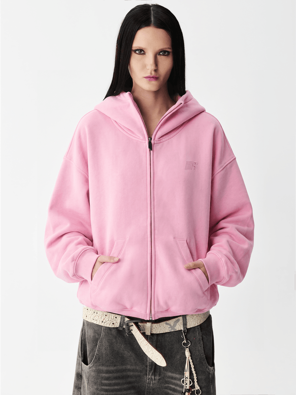 Close-up shot of a female model wearing a pink hoodie with the hood pulled up over the face.