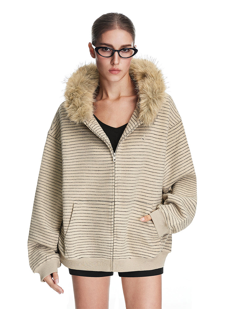 Full view of model in beige oversized fuzzy jacket with faux fur hood, minimalist industrial streetwear style.