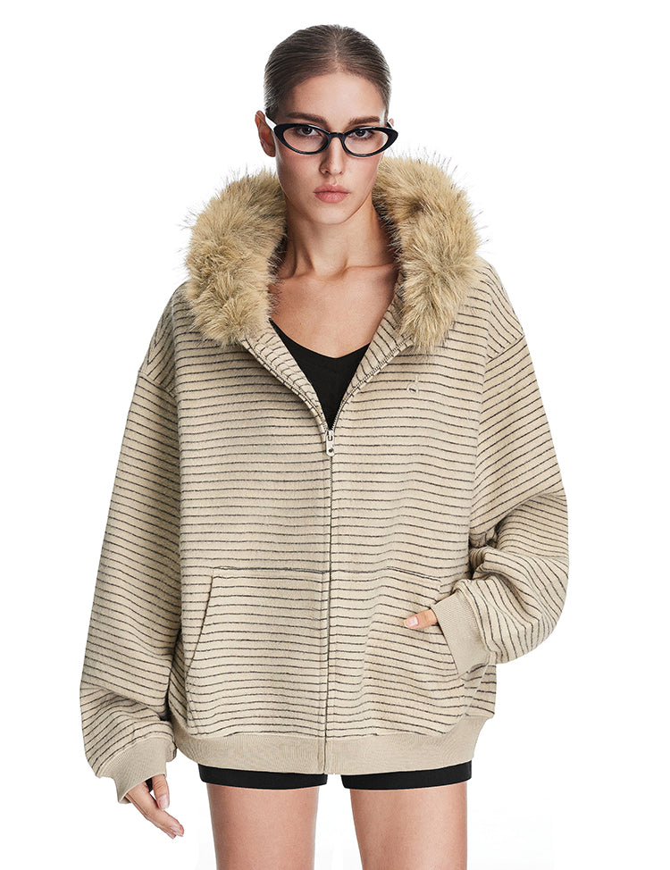 Full view of model in beige oversized fuzzy jacket with faux fur hood, minimalist industrial streetwear style.