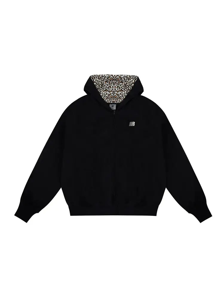 Flat lay of black zip-up hoodie with leopard print lined hood and cat ears on white background.
