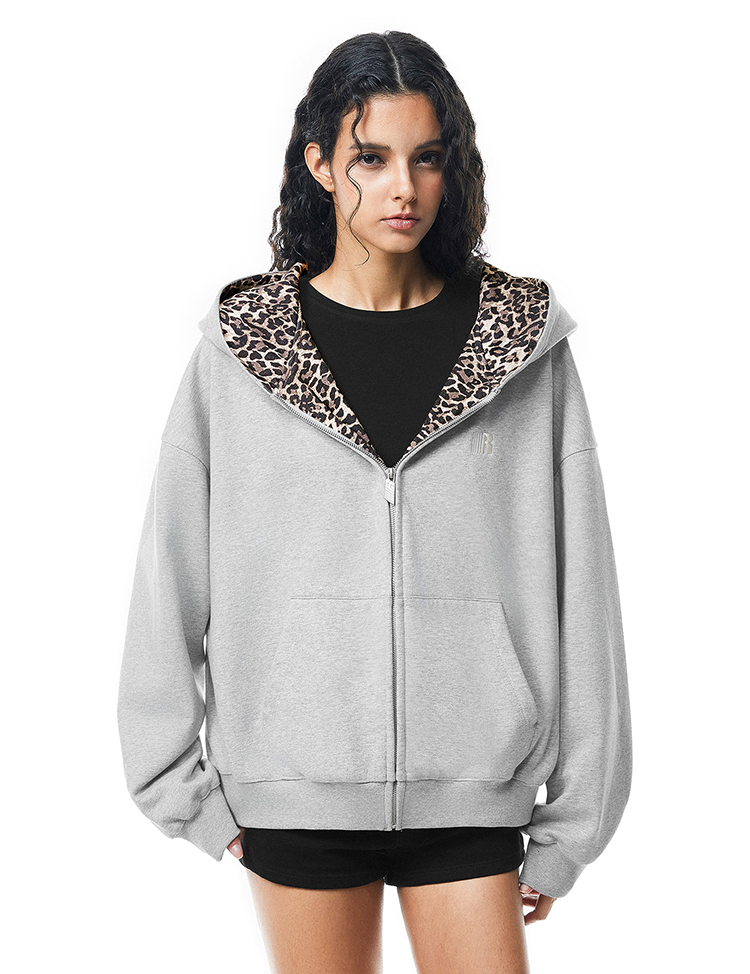 Model in grey zip-up hoodie featuring a leopard print lined hood with cute cat ears, Y2K streetwear aesthetic.