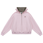 Flat lay of pink cropped zip-up hoodie with leopard print lined hood and cat ears, pastel edgy fashion.