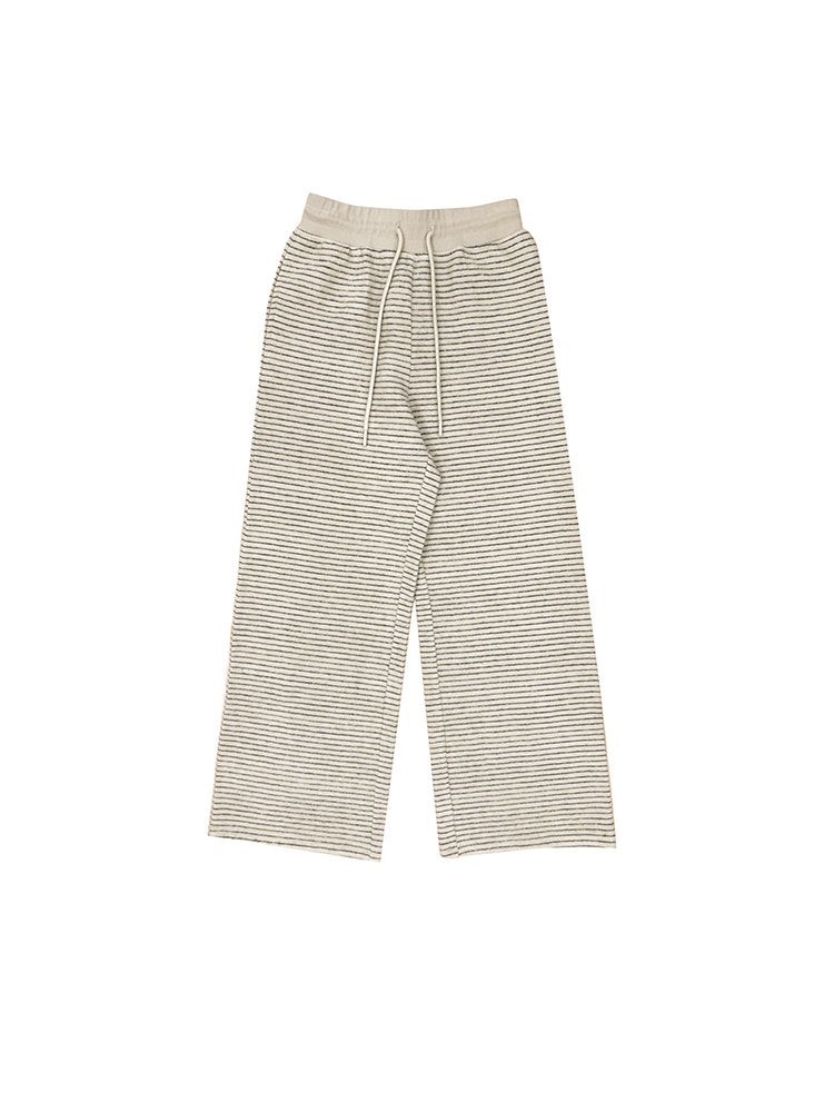 Studio flat lay of the cream-colored textured wide-leg pants on a white background, showing the full length and elastic drawstring waistband.