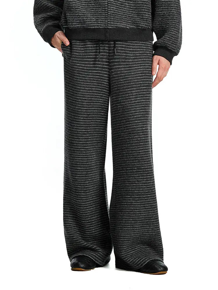 A model wearing charcoal black wide-leg textured pants paired with a matching dark sweatshirt, showcasing a coordinated monochrome lifestyle look.