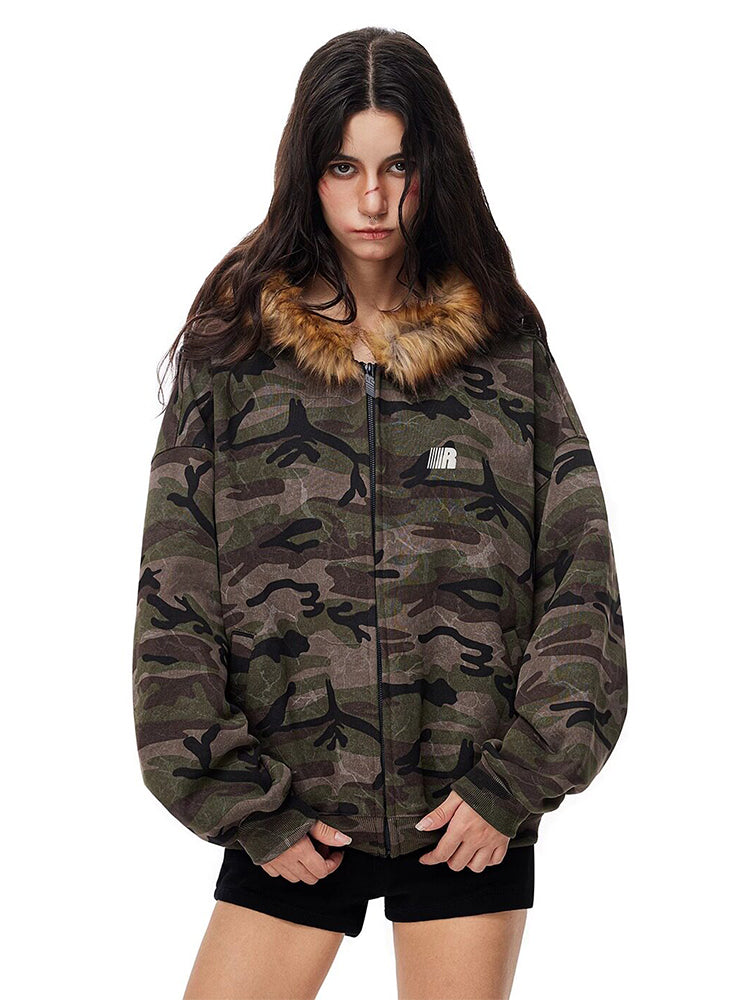 Full body shot of model styling camo jacket with black shorts and chunky boots.
