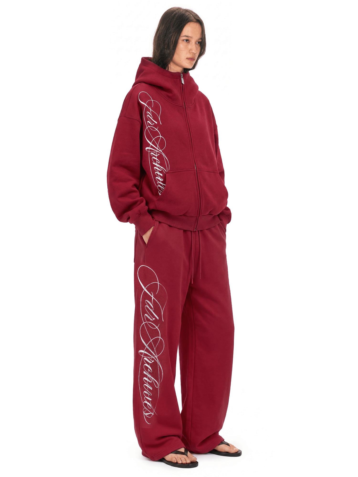 Model in burgundy zip hoodie and matching wide-leg track pants, side angle view