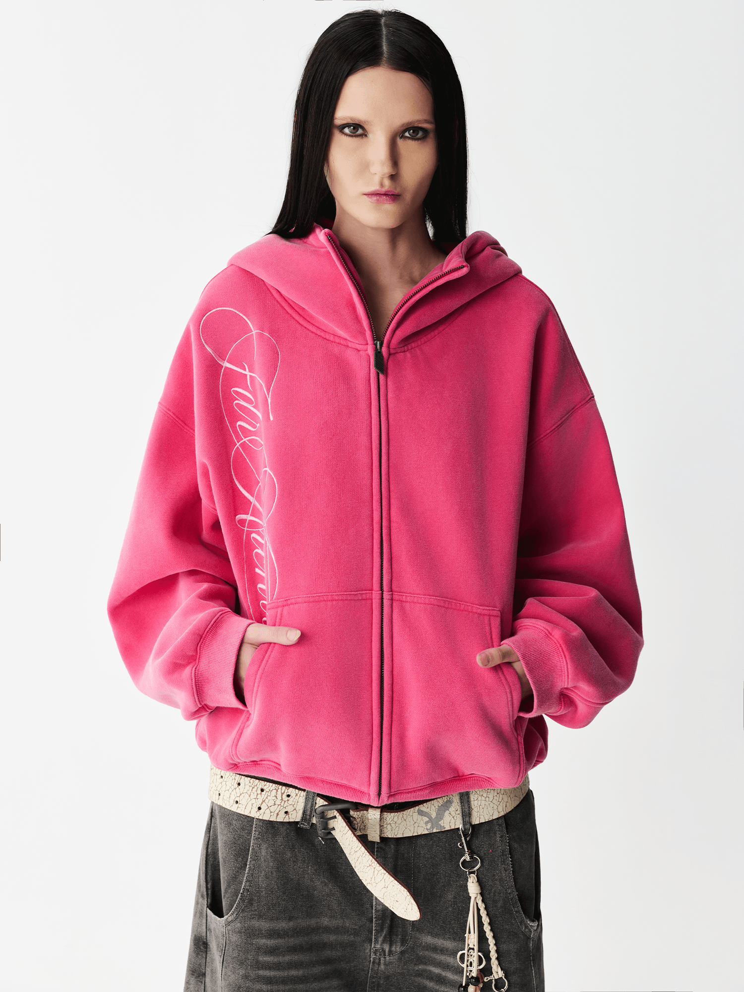 Front half-body view of a female model wearing a washed pink embroidered zip-up hoodie.