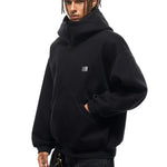 Side profile of model in black hoodie, highlighting the structured hood and heavyweight fabric texture.