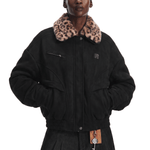 Person wearing a black coat with a leopard print collar on a white background