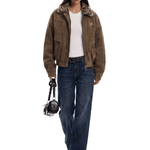 Person wearing a brown jacket with fur trim, white shirt, and blue jeans on a white background