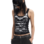 Mid-shot close-up of a model wearing the black graphic tank top and black pants, looking down.