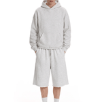 Full-body front view of a model wearing a light gray hoodie and matching shorts, paired with white socks and light-colored sneakers.