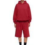 Full-body front view of a model wearing a dark red hoodie and matching shorts, paired with black socks and black shoes.