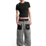 Full-body front view of a male model wearing grey leopard print wide-leg trousers and a black t-shirt for a street-style look.