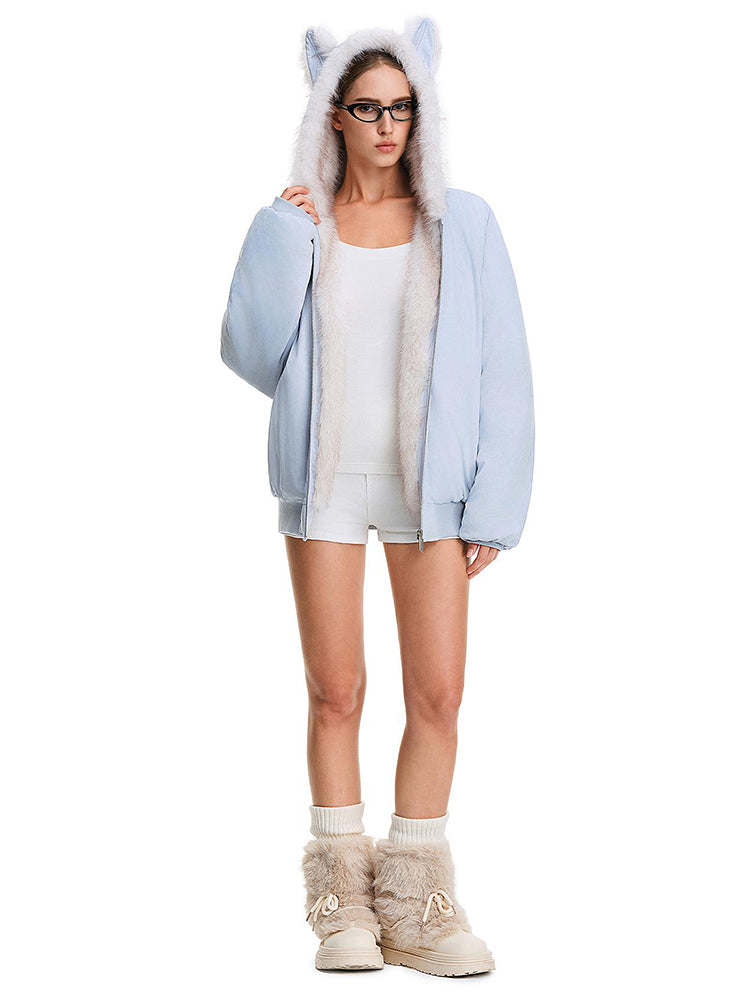 Ganzkörperaufnahme einer Modelin, die in einer hellblauen Damen-Felljacke mit Kapuze posiert und bei der die weiße Borte hervorgehoben wird