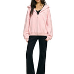 Full length shot of model in pink oversized hoodie and flared black trousers