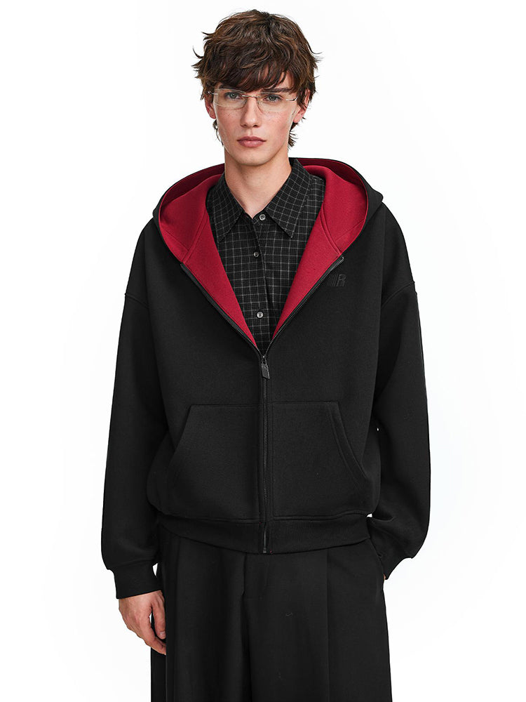 Model wearing black zip-up hoodie with red interior lining, streetwear aesthetic style.