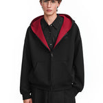 Model wearing black zip-up hoodie with red interior lining, streetwear aesthetic style.