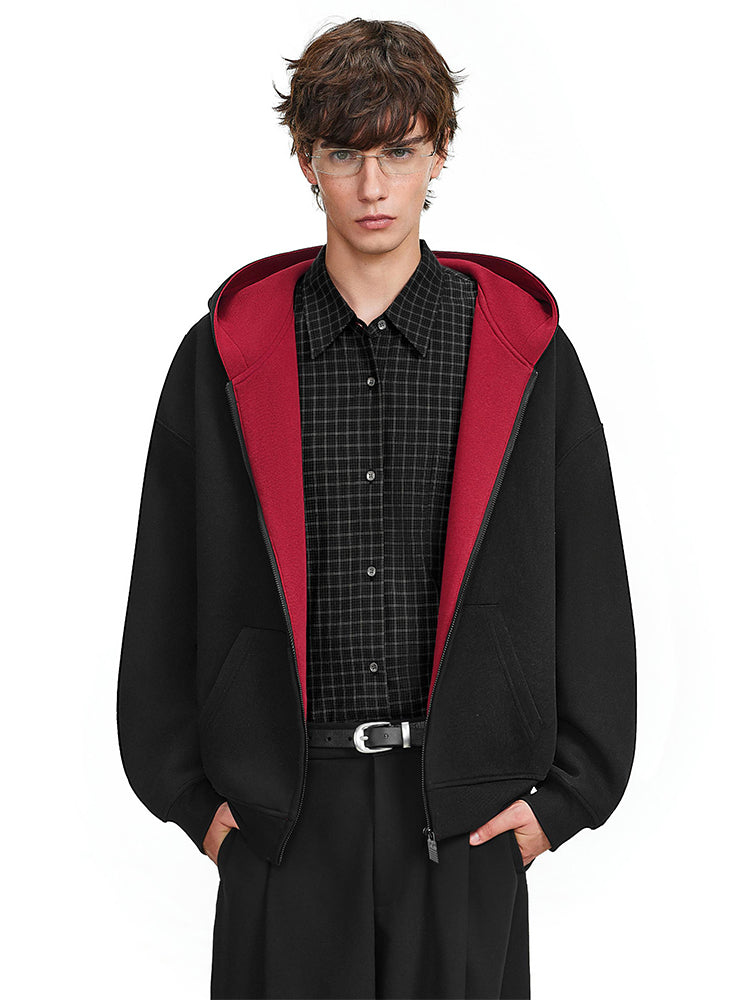 Front view of minimalist black hoodie with bold red contrast hood, oversized urban fashion.