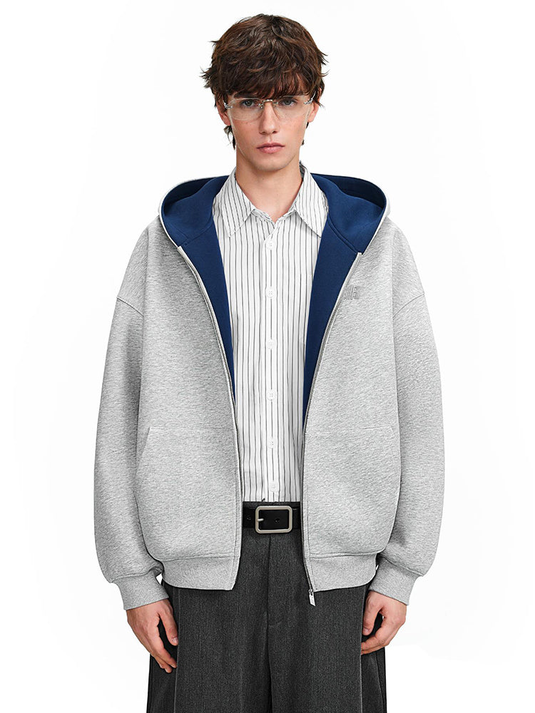 Street style shot of a model in a grey hoodie with navy lining, focusing on the boxy silhouette and layered collar.