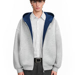 Street style shot of a model in a grey hoodie with navy lining, focusing on the boxy silhouette and layered collar.