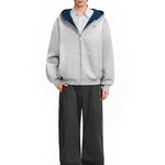 Male model wearing a grey heavy-weight hoodie with deep navy blue contrast lining, minimalist techwear look.