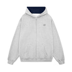 Flat lay of a grey oversized zip-up hoodie featuring a dark navy contrast hood interior.
