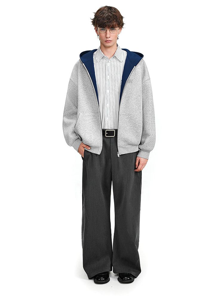 Full body view of a grey zip-up jacket with navy interior styled with baggy black trousers.