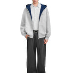 Full body view of a grey zip-up jacket with navy interior styled with baggy black trousers.