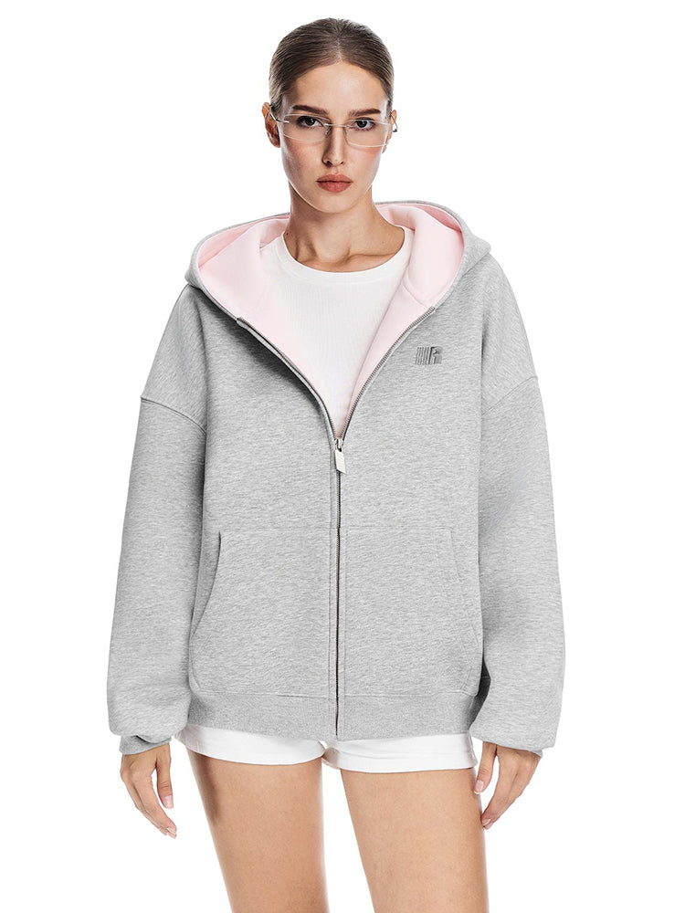 Full length shot of a grey zip-up hoodie with baby pink hood interior styled with white shorts.