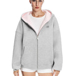 Full length shot of a grey zip-up hoodie with baby pink hood interior styled with white shorts.
