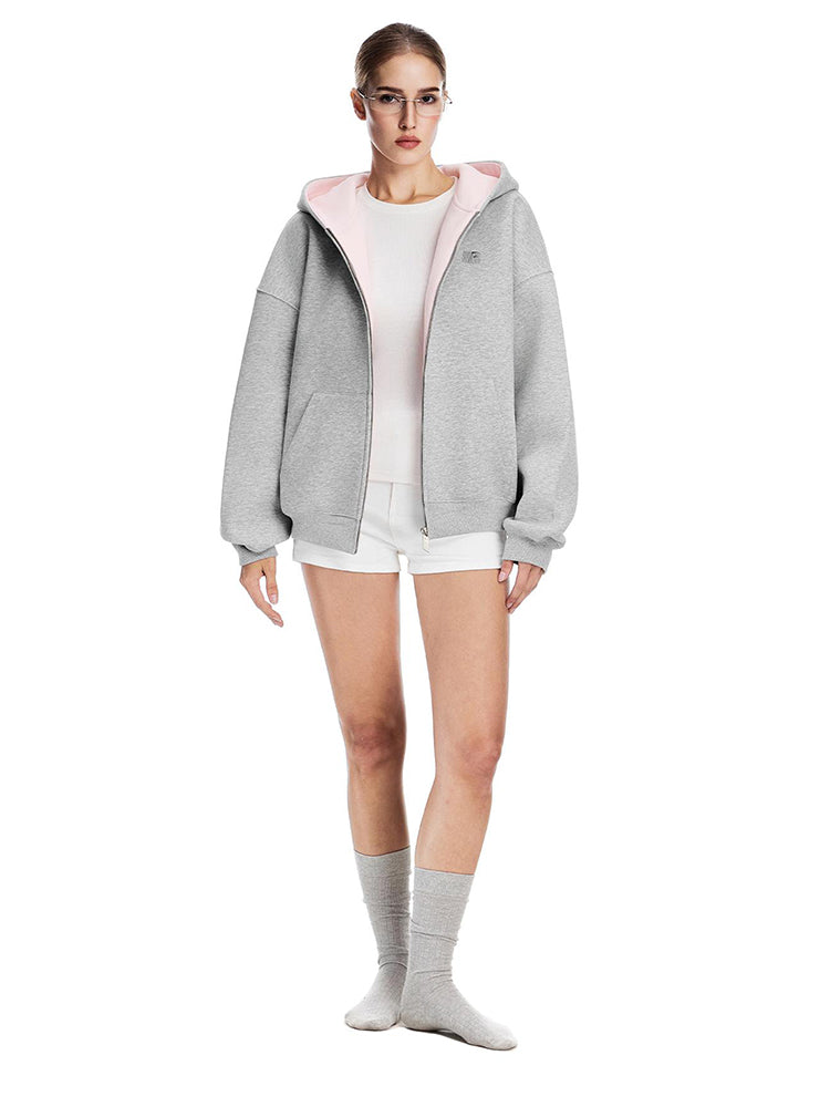 Model wearing a heather grey oversized hoodie featuring a soft pink contrast lining, edgy soft-girl aesthetic.