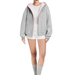 Model wearing a heather grey oversized hoodie featuring a soft pink contrast lining, edgy soft-girl aesthetic.