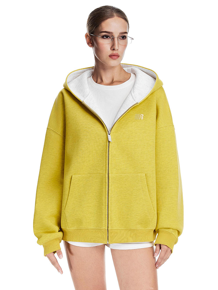 Close-up shot of a boxy yellow hoodie with white hood interior worn by a female model.