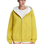Close-up shot of a boxy yellow hoodie with white hood interior worn by a female model.