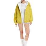 Full body shot of a model styling a yellow oversized hoodie with white lining and high socks, urban Y2K vibe.