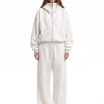 Full-length shot of a model styling an off-white unisex baggy streetwear tracksuit with vibrant yellow shoes, clean aesthetic techwear vibes.