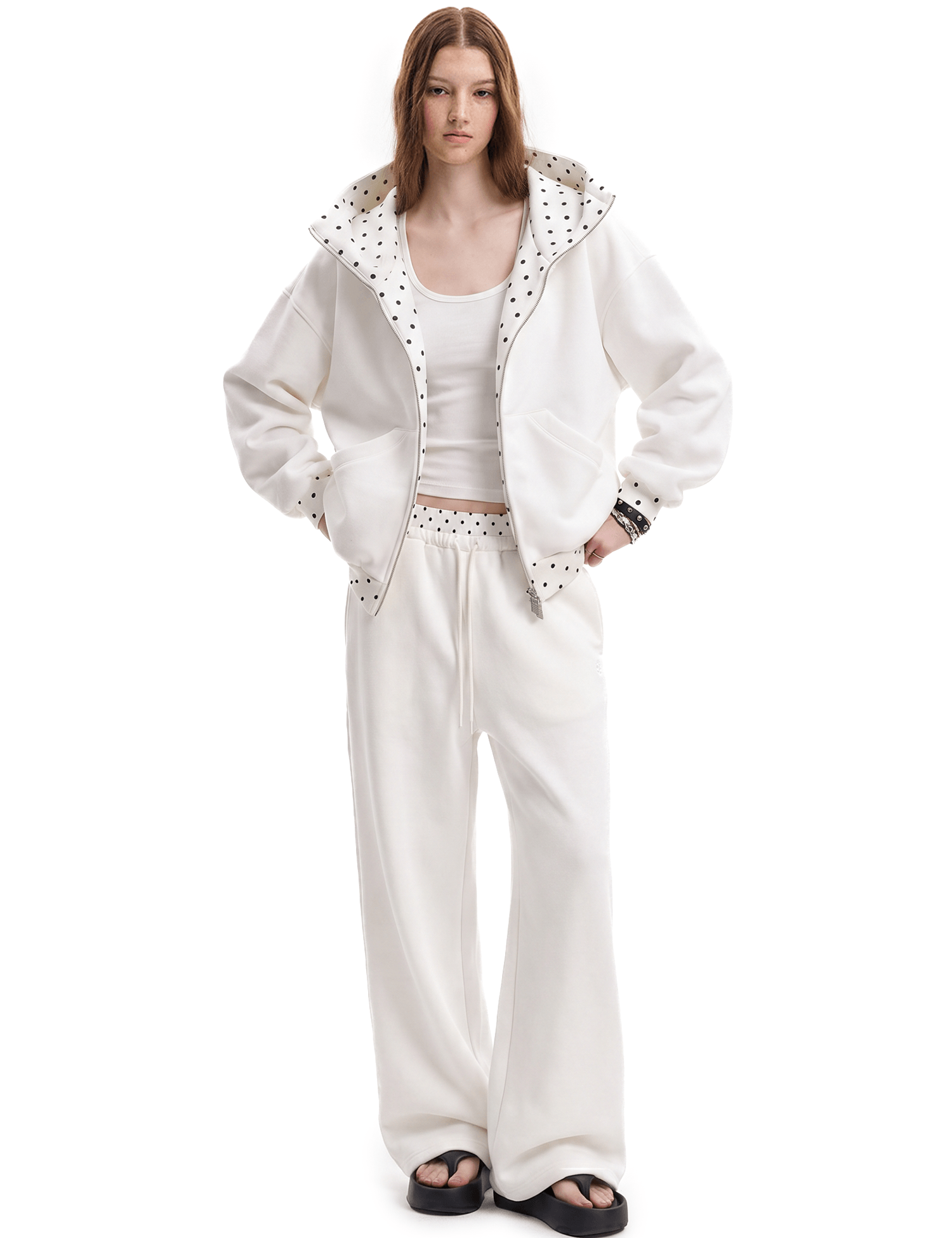 Front view of a model wearing a unisex off-white high-street streetwear tracksuit, featuring an oversized zip-up hoodie with a textured lining and matching baggy sweatpants.