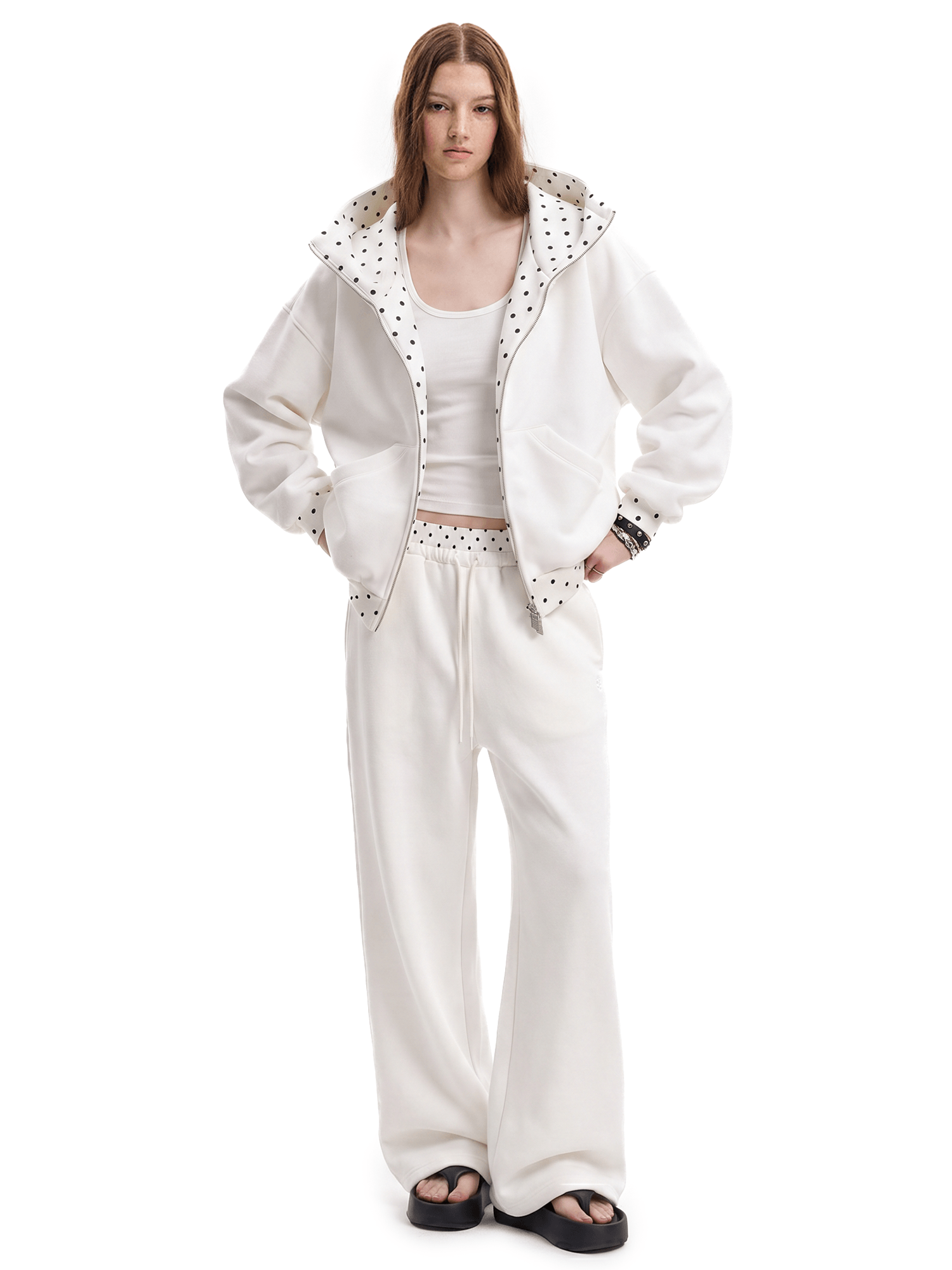 Front view of a model wearing a unisex off-white high-street streetwear tracksuit, featuring an oversized zip-up hoodie with a textured lining and matching baggy sweatpants.