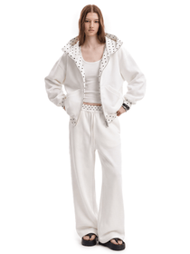 Front view of a model wearing a unisex off-white high-street streetwear tracksuit, featuring an oversized zip-up hoodie with a textured lining and matching baggy sweatpants.