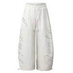 Angled view of baggy white joggers highlighting the voluminous wide-leg silhouette.