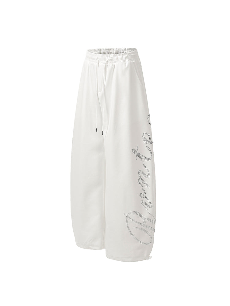 Front view of white oversized wide-leg sweatpants with subtle grey graphic print.