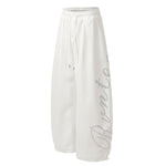 Front view of white oversized wide-leg sweatpants with subtle grey graphic print.