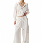 Female model wearing white oversized zip-up hoodie and matching wide-leg sweatpants set.