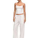 Full body shot of model wearing FDR Studios sleek off-white camisole top and loose loungewear trousers.