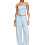 Woman wearing a light blue strapless top and wide-leg pants on a white background