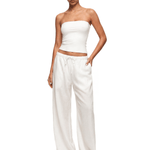 Woman wearing a white strapless top and wide-leg pants on a white background
